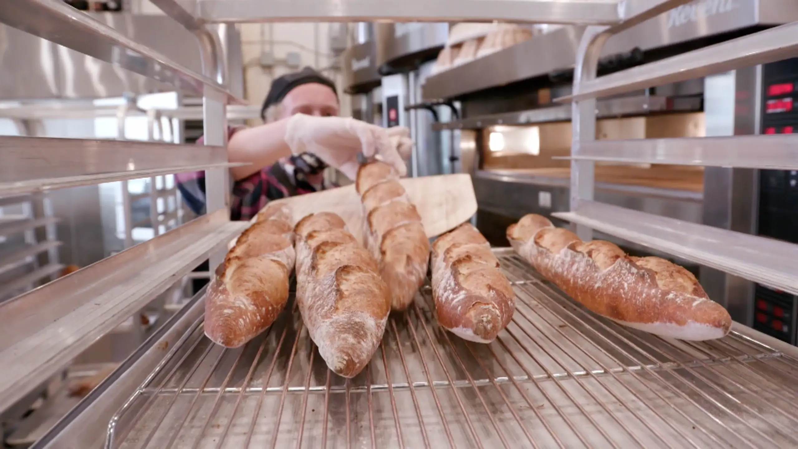 Baker removing baguette from the oven